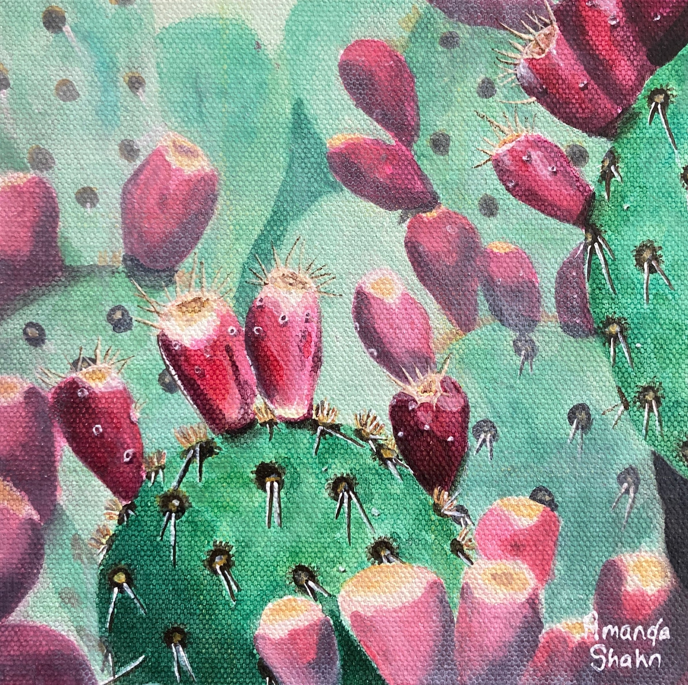 Framed artwork of a cactus with pink flowers on a green background.